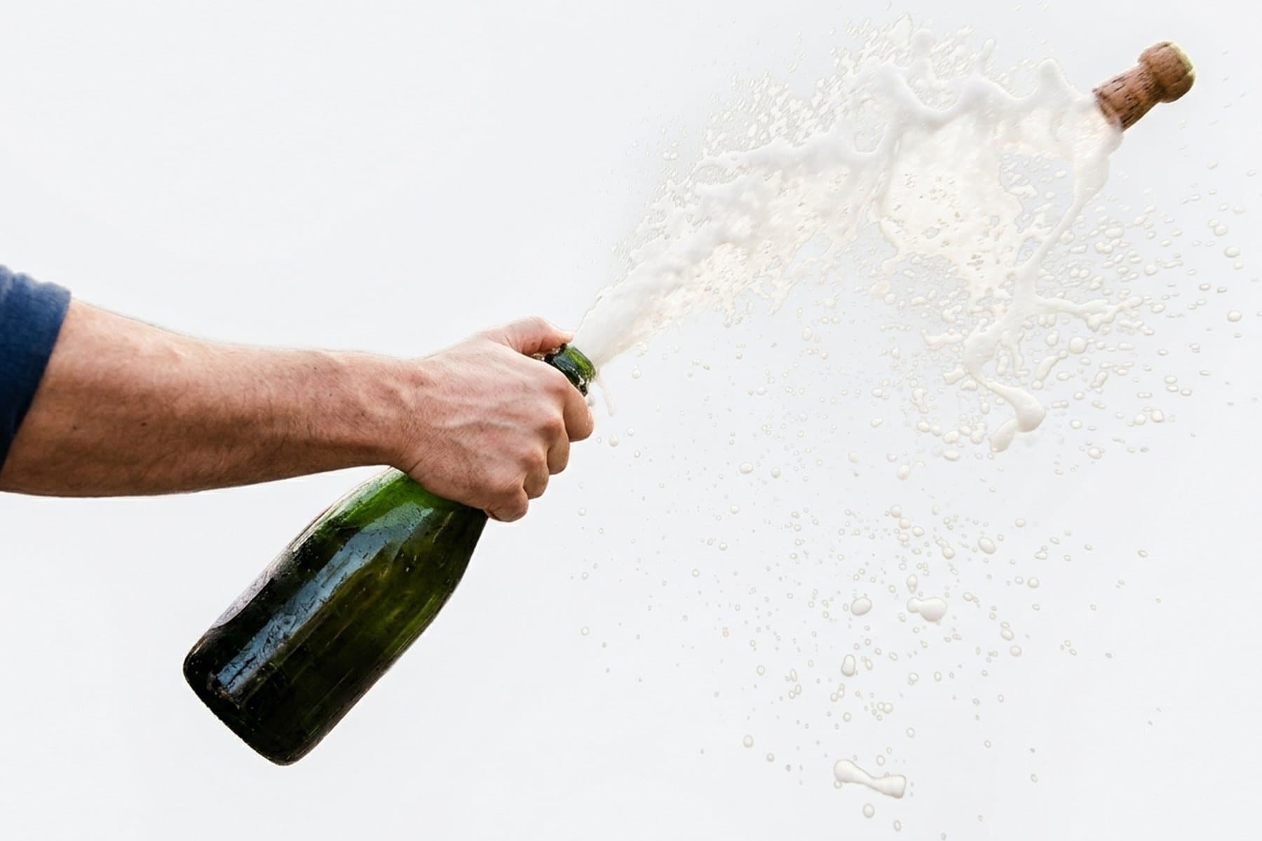 A bottle of champagne spraying as the cork leaves it